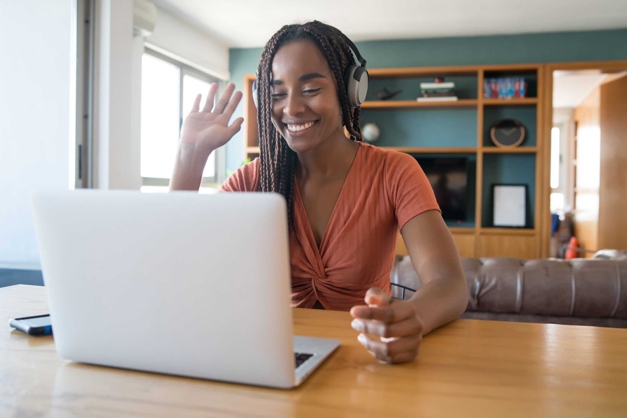 Portrait of a woman on a video call with laptop and headphones while working from home. Home office concept. New normal lifestyle.