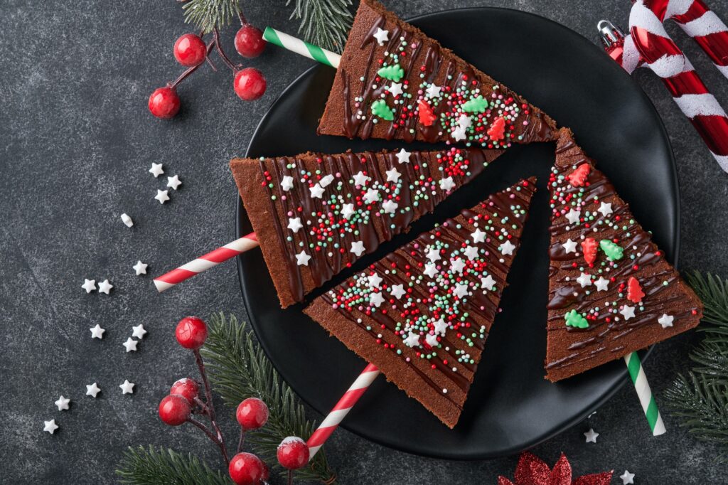 Chocolate brownies Christmas tree with chocolate icing and festive sprinkles on stone table. Christm