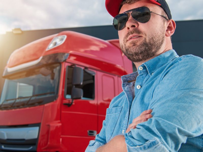Caucasian Semi Truck Driver in His 30s Portrait in Front of His Tractor Truck. Heavy Duty Transportation Industry Theme.
